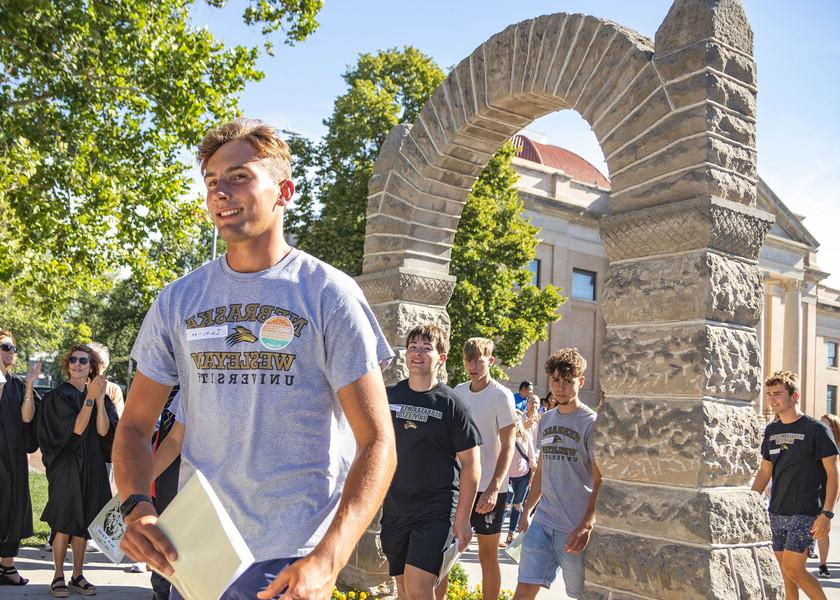 Students walk thru the stone arch with faculty, staff and parents cheering.